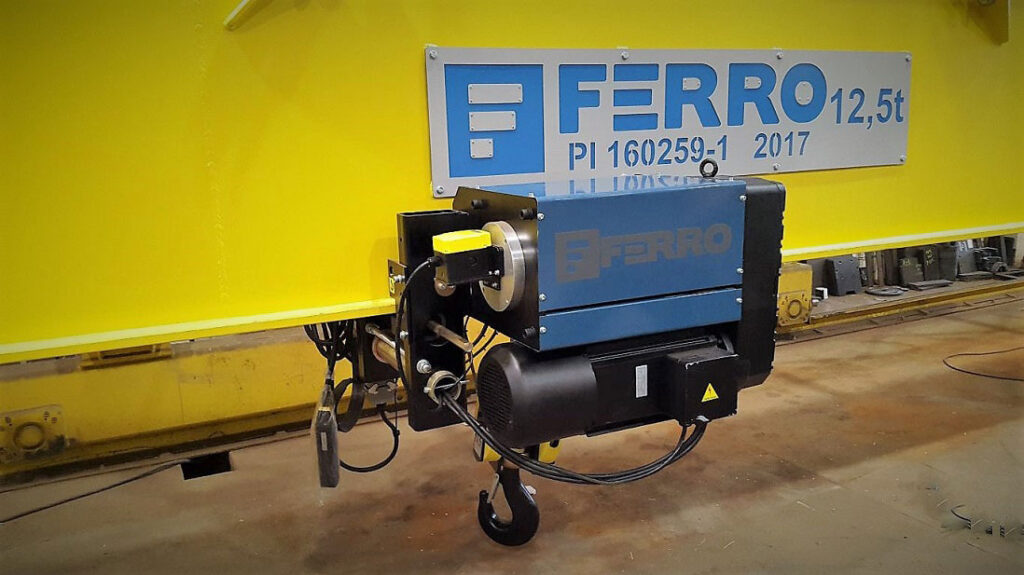 Talha elétrica industrial utilizada para elevação de cargas pesadas, equipada com motor elétrico e gancho de içamento. 